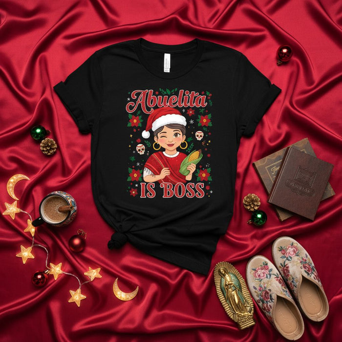 Camiseta navideña Abuela Es La Jefa con gorro de Santa, abuela guiñando con elote, calaveras de azúcar, flor de pascua y diseño festivo para regalo de abuela hispana