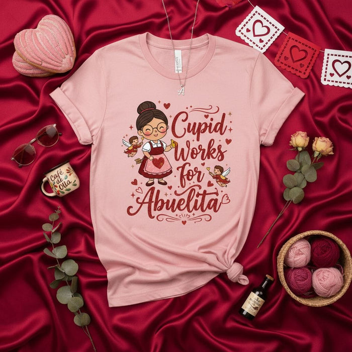 Cupid Works For Abuelita T-Shirt, Cute Spanish Grandma Valentine's Day Tee, Abuela Love Shirt, Hispanic Grandmother Gift, Mexican Mama Day of Love Pink Unisex Shirt Mexicada