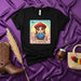 LA GAUCHA Lotería Card T-Shirt: Cute Cartoon Cowgirl Graphic Tee, Argentine South American Gaucho Culture Shirt, Traditional Beret and Lasso Design, Unisex Black Shirt with Colorful Print Mexicada