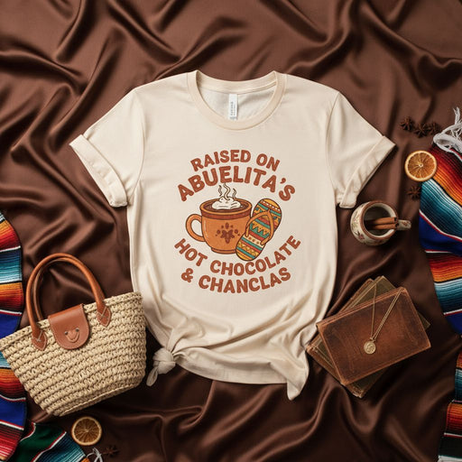 Raised on Abuelita's Hot Chocolate & Chanclas T-Shirt, Funny Hispanic Grandma Culture Tee, Latinx Heritage Gift, Cozy Abuela Quote Shirt, Mexican American Family Humor Apparel, Soft Cream Unisex Graphic Top Mexicada